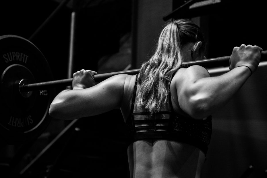 Woman with barbell on her traps ready to squat